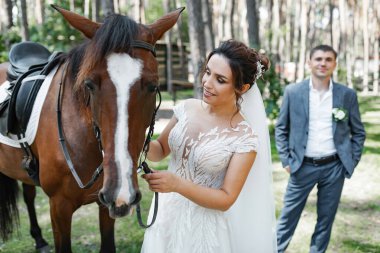 Genç ve evli bir çift ormanda yürüyüşe çıkmış kahverengi bir atla..