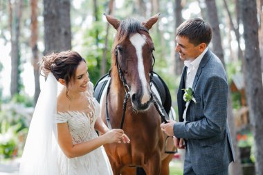 Genç ve evli bir çift ormanda yürüyüşe çıkmış kahverengi bir atla..
