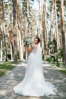 Çam ormanında elinde güzel bir buketle poz veren Avrupalı bir gelin..