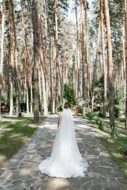 Çam ormanında elinde güzel bir buketle poz veren Avrupalı bir gelin..