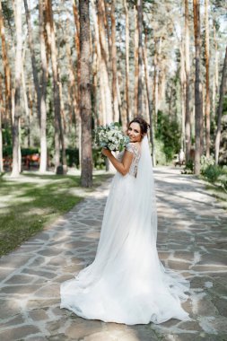 Çam ormanında elinde güzel bir buketle poz veren Avrupalı bir gelin..