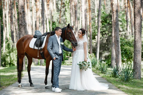Genç ve evli bir çift ormanda yürüyüşe çıkmış kahverengi bir atla..