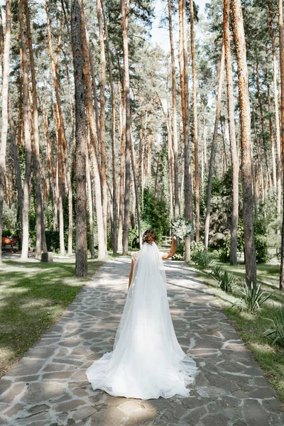 Çam ormanında elinde güzel bir buketle poz veren Avrupalı bir gelin..