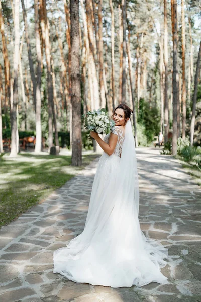 Çam ormanında elinde güzel bir buketle poz veren Avrupalı bir gelin..