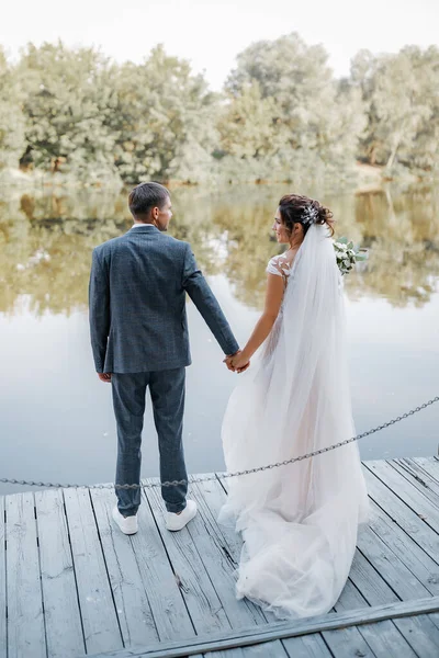 Svatební Pár Usměje Zastaví Před Kamerou Řeka Pozadí Nevěsta Svatební — Stock fotografie