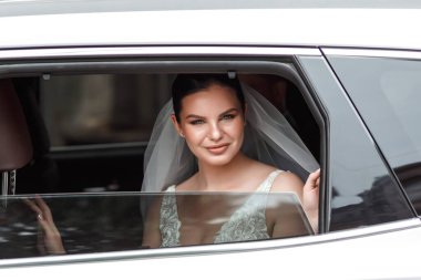 Mutlu gelin arabanın camından dışarı bakar..
