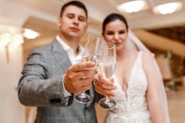 Düğün çifti güzel bir pozla poz veriyor. Mutlu gelin. Arka planda büyük bir avize