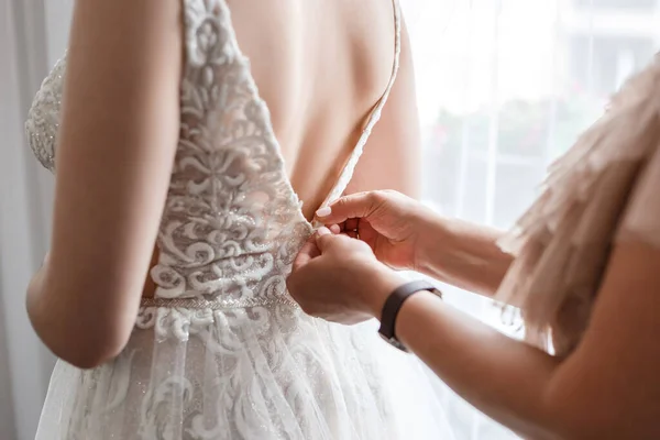 A mother fastens her daughter\'s dress, wedding details. Back view