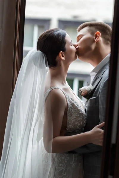 新婚夫妇在阳台上亲吻 自然的阳光 新娘的长面纱 — 图库照片