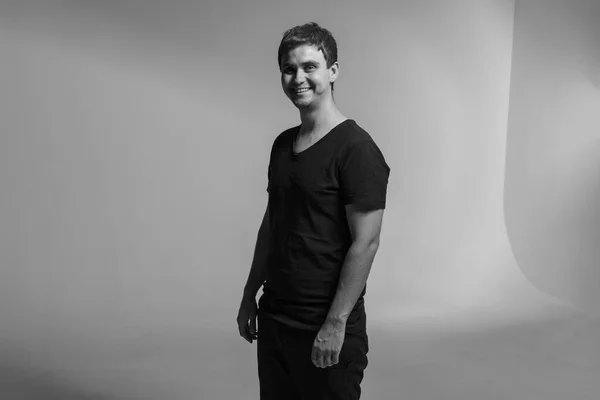 Portrait of a smiling man in a black T-shirt, posing in a photo studio. Colorful background