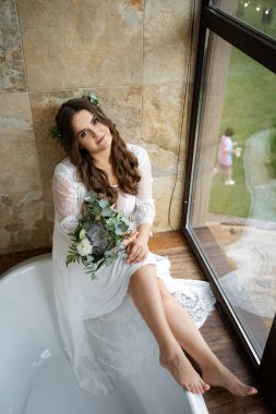 Odada ayyaş, çekici bir gelin var. Gelinlik giymiş şık bir kız ve gelin buketi..