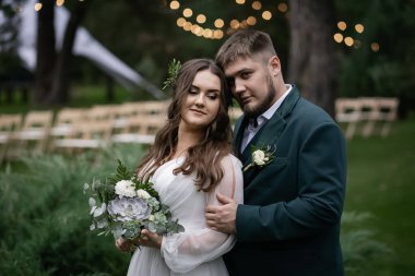 Kıvrımlı insanlar, yürüyüş yapan bir çift. Zarif bir gelin, yeşil takım elbiseli bir damat. Güzel park