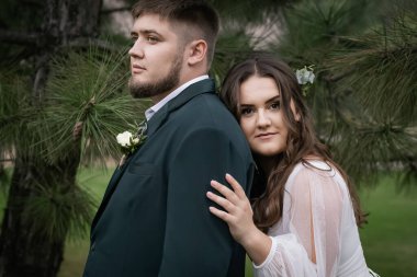 Kıvrımlı insanlar, yürüyüş yapan bir çift. Zarif bir gelin, yeşil takım elbiseli bir damat. Güzel park