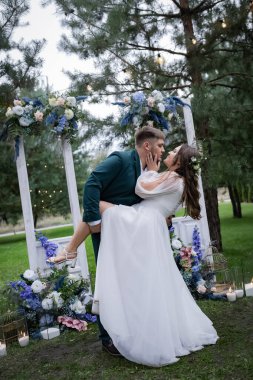 Kıvrımlı insanlar, yürüyüş yapan bir çift. Zarif bir gelin, yeşil takım elbiseli bir damat. Güzel park