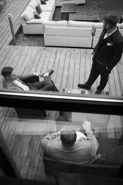 Three men chatting on the street, smoking and drinking alcohol. View from above
