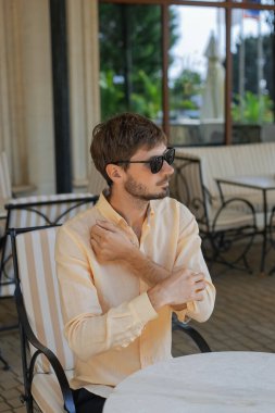 Turuncu gömlek ve güneş gözlüğü takan Avrupalı bir adam. Sıcak yaz mevsiminde tropikal bir ülke. 