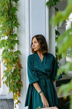 Turkuaz bir elbiseyle gülümseyen, sofistike bir kız iyi korunmuş yeşil bir parkta yürüyor. Tropikal bir ülkede sıcak bir yaz.. 