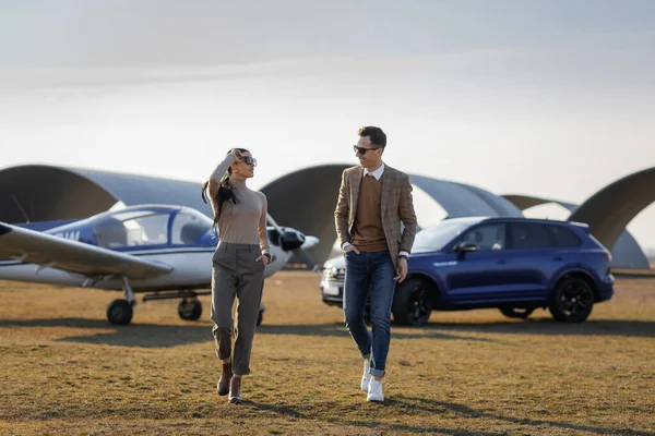 日落在机场 蓝色的吉普和飞机 漂亮时髦的一对富有的夫妇 买车时的快乐心情 图库图片