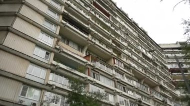 Sıra dışı balkonları olan yüksek katlı bir binanın ön cephesi. Alışılmadık bir ev. Alt manzara. Doli kamera görüntüsü