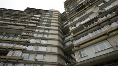 Yüksek bir konut binasında alışılmadık balkonlar, aşağıdan manzara. Binanın garip geometrisi. Doli kamera. 