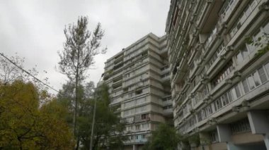 Sıra dışı balkonları olan yüksek katlı bir binanın ön cephesi. Alışılmadık bir ev. Alt manzara. Doli kamera.