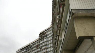 Sıra dışı balkonları olan yüksek katlı bir binanın ön cephesi. Alışılmadık bir ev. Alt manzara. Doli kamera.
