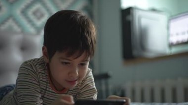 Çocuk aktif olarak odada tek başına akıllı telefon oynuyor. Bir genç bu aleti hevesle çalar. El ele.