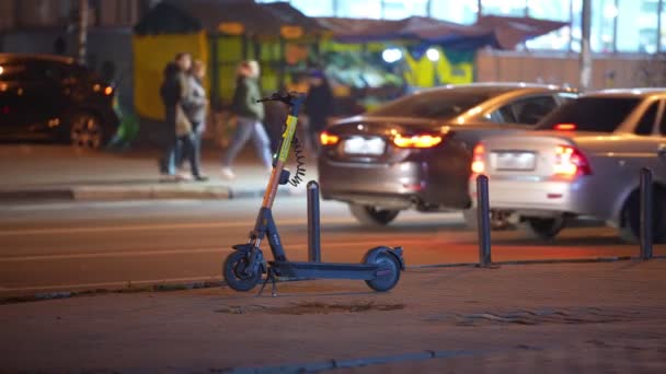 Электрический скутер припаркован возле проезжей части ночью. Осенняя погода — стоковое видео