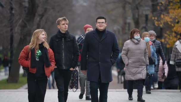 Moskova, Venäjä - marraskuu 2021: Ryhmä nuoria teinejä eri tyyliin pukeutuneina kävelee puistossa lukituksen jälkeen. Hidastus — kuvapankkivideo