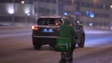 Moskova, Rusya - Aralık 2021: Kışın, kar yağışı sırasında yoldaki bisikletli kurye. Kışın bisikletle kurye.