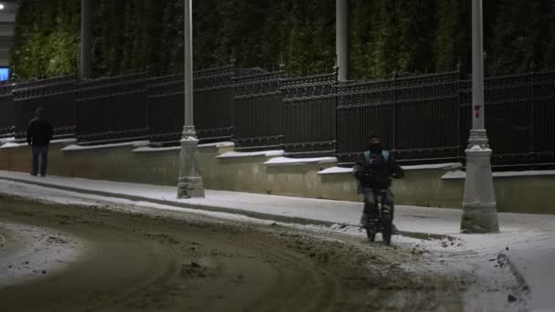 モスクワ,ロシア- 2021年12月:雪の中、道路上の自転車で冬の夜に宅配便。冬は自転車で移動 — ストック動画
