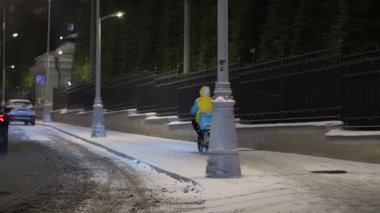 Moskova, Rusya - Aralık 2021: Kışın, kar yağışı sırasında yoldaki bisikletli kurye. Kışın bisikletle kurye.