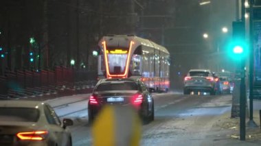 Moskova, Rusya-Aralık 2021: Modern bir tramvay kış aylarında bir gece caddesinde ilerliyor.