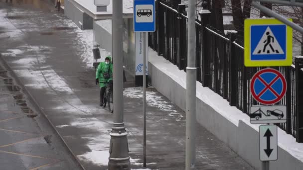 Moskwa, Rosja - grudzień 2021: Kurier na rowerze zimą. Kurier na rowerze dostarcza zimą podczas opadów śniegu. Zwolniony ruch — Wideo stockowe
