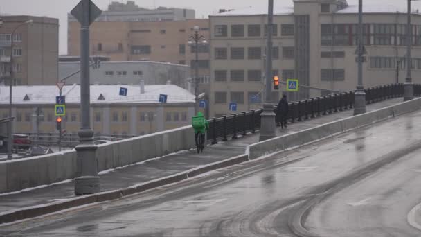 Moskau, Russland - Dezember 2021: Fahrradkurier im Winter. Ein Kurier auf dem Fahrrad liefert im Winter bei Schneefall aus. Zeitlupe — Stockvideo