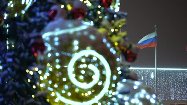 Η σημαία της Ρωσίας στο διοικητικό κτίριο μέσα από παιχνίδια στο χριστουγεννιάτικο δέντρο το χειμώνα τη νύχτα. Επιλεκτική εστίαση — Αρχείο Βίντεο