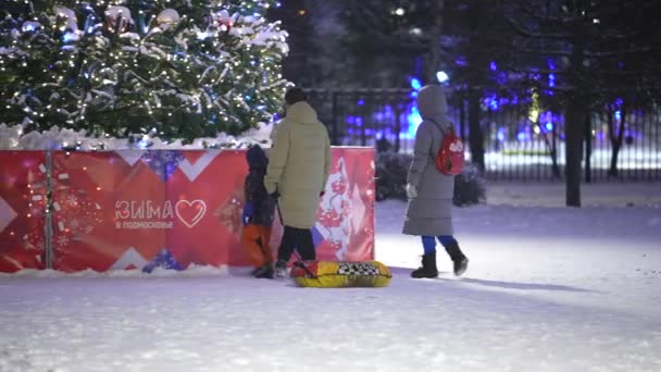 Moskou, Rusland-december 2021: Een jong gezin nadert 's nachts een met speelgoed versierde kerstboom — Stockvideo