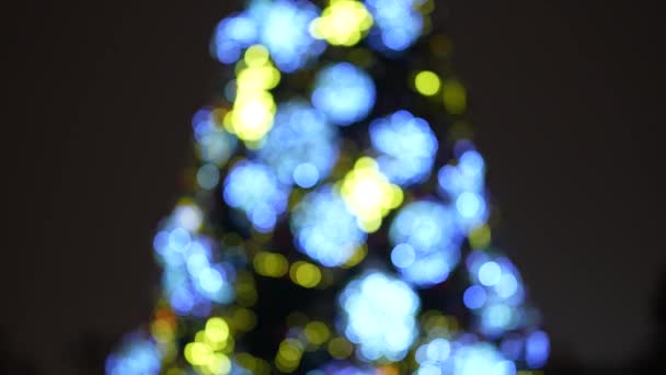 Vánoční strom v ohnisku na pozadí městského života v zimě v noci — Stock video