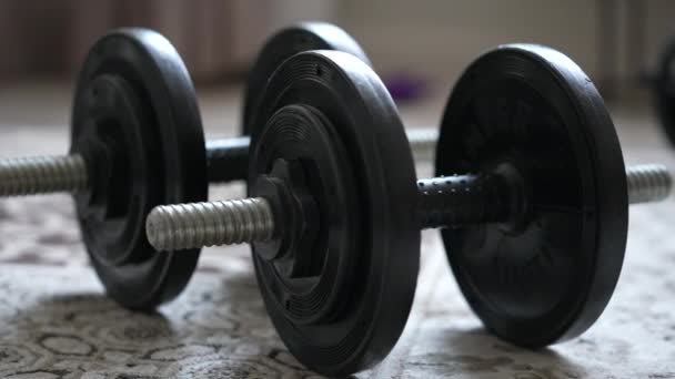 Dumbbells collapsible lie in the room on the carpet at home clouse up. Dolly camera shot — Vídeo de Stock