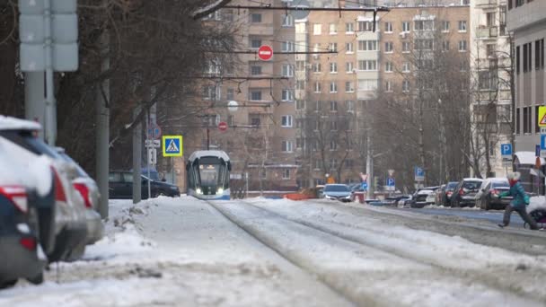 러시아 모스크바 - 2022 년 1 월: 한 어린아이가 폭설이 내린 도시에서 교통 법규를 어기며 철도를 건너고 있다 — 비디오