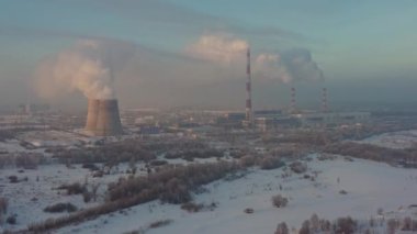 The thermal power plant works at full capacity in the cold winter during the day near the city. Aerial view