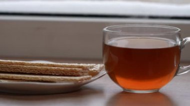 A large mug of tea and diet bread in a plate on the windowsill in winter. The camera is in motion. Selective focus