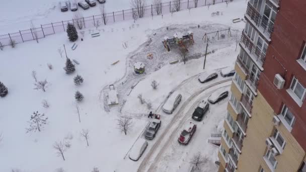 Sněhová frézka odstraňuje sníh na hřišti pomocí speciálního vybavení na nádvoří obytné budovy. Letecký pohled — Stock video