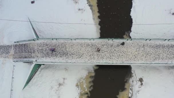 El puente peatonal de la ciudad, la gente camina a través del puente sobre el río en invierno. Vista aérea — Vídeos de Stock