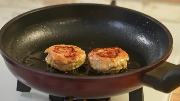 Duas costeletas de frango fritam-se em uma panela de ato de fritar preta no azeite — Vídeo de Stock