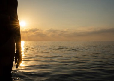 Kız şafak vakti kıyıda duruyor.