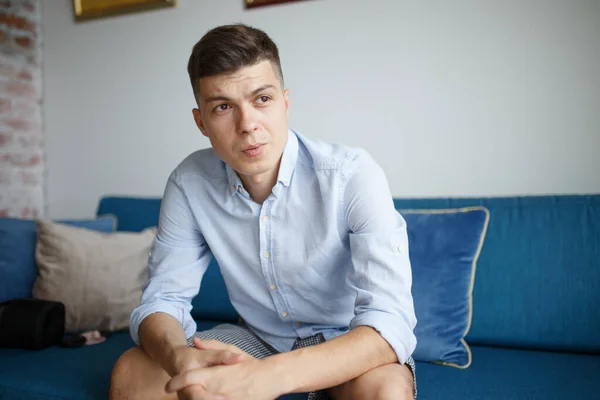 Jovem Senta Sofá Quarto Casa Com Uma Camisa Azul Joelhos — Fotografia de Stock