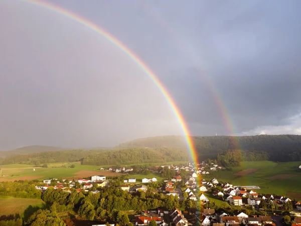 Rainbow over the houses in the village and the field double rainbow after the rain in the German village German wooden houses without people sunset sky and rain street. A quiet village with beautiful