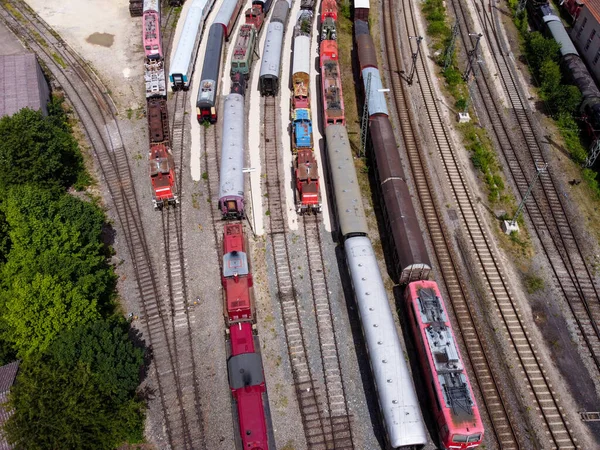 Cargo trains close-up. Aerial view of colorful freight trains on the railway station. Wagons with goods on railroad. Heavy industry. Industrial conceptual scene with trains. Top view flying drone.