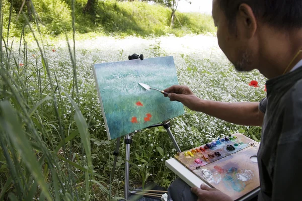 Pintor pinta flores no campo — Fotografia de Stock